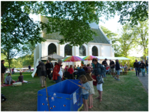 Bezoekers op de Shop & Foodmarkt in Groet met het witte kerkje van Groet op de achtergrond